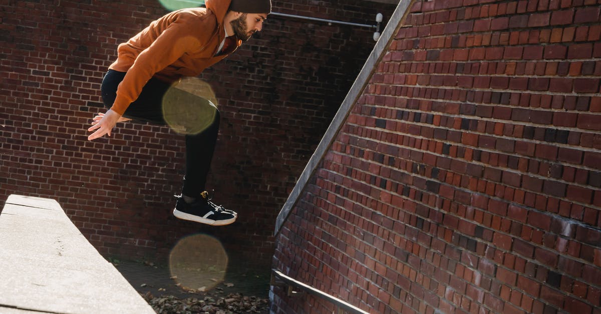 Does having a land border with an AI player increase the risk that it will dislike me? - Full body side view of fearless bearded male jumping off concrete border near brick walls on street during sportive training