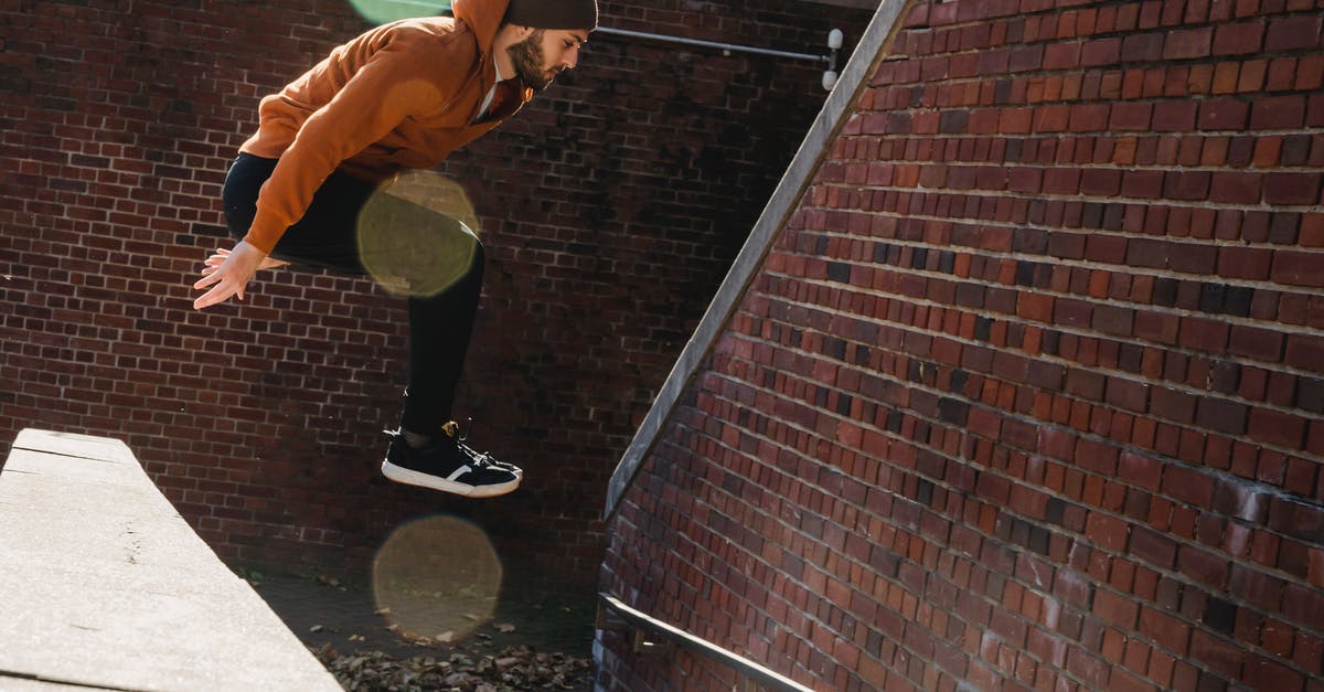 Does having a land border with an AI player increase the risk that it will dislike me? - Full body side view of fearless bearded male jumping off concrete border near brick walls on street during sportive training