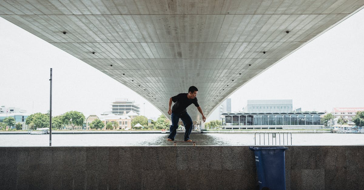 Does having a land border with an AI player increase the risk that it will dislike me? - Full body of unrecognizable male riding on skateboard on railing near sea under bridge during training on seaside in city