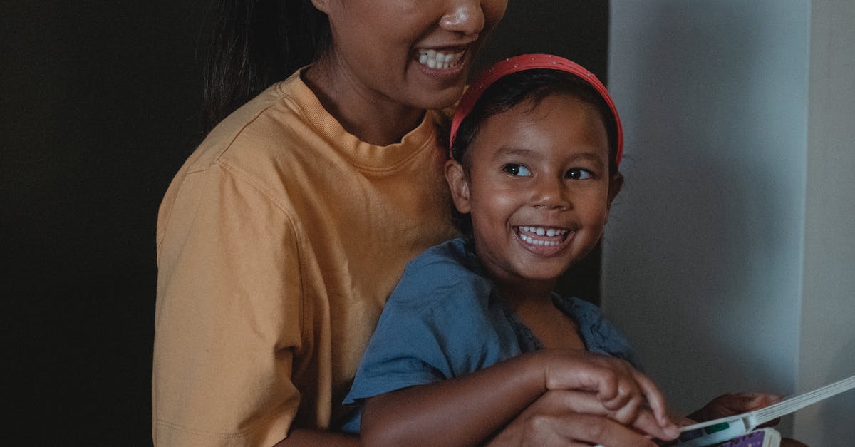 Does Lynchwood have any story related quests? - Smiling ethnic crop woman hugging playful girl while reading interesting story together near black wall during free time in apartment