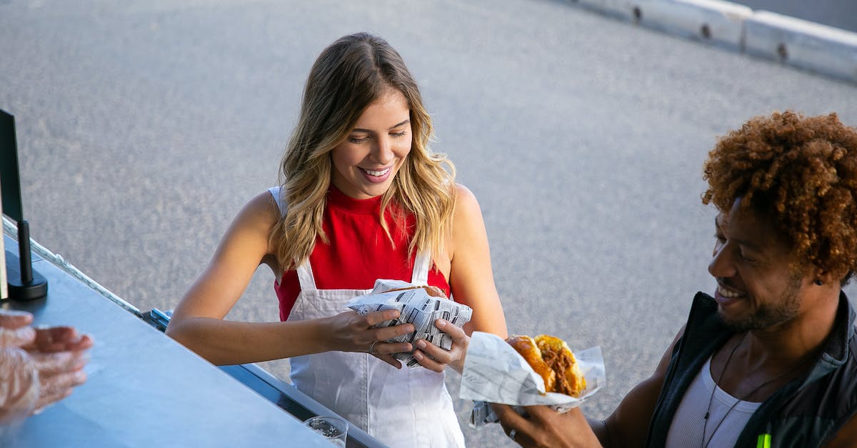 Does my truck slow down when there are zombies on it? - From above of positive multiethnic couple eating tasty burgers wrapped in paper at food truck