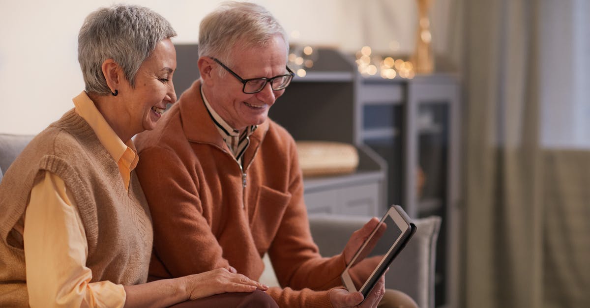 Does PES/FIFA support online multiplayer for older versions? - Couple Smiling While Looking at a Tablet Computer