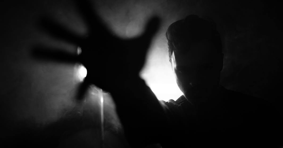 Does silence affect hero passives? - Black and white of anonymous male reaching out hand to camera while standing near wall with lamp in dark room