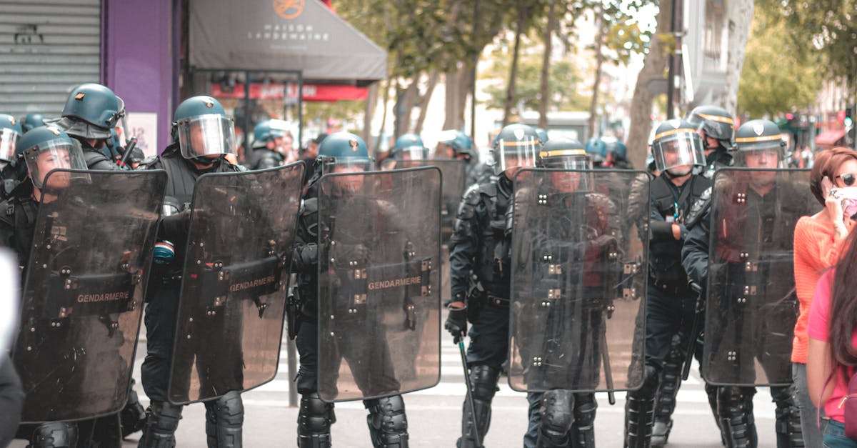 Does soldier rank matter? - Group of soldiers in police uniforms and helmets walking along street and protecting people near protest