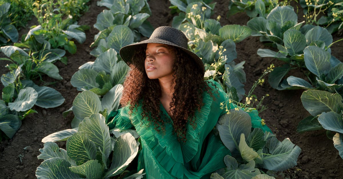Does straw hat and other overheat-slowing items increase heat drain during winter? - Woman in Brown Straw Hat and Green Dress Sitting in Cabbage Field
