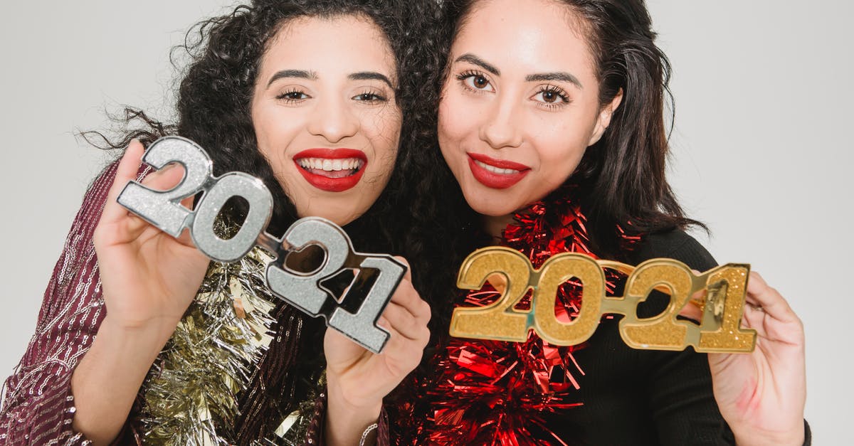 Does the assigned Vault Number have significance beyond identification? - Cheerful women with dark hair in festive clothes with tinsels showing decorative numbers 2021 during New Year celebration against light wall Does the assigned Vault Number have significance beyond identification? - Cheerful women with dark hair in festive clothes with tinsels showing decorative numbers 2021 during New Year celebration against light wall