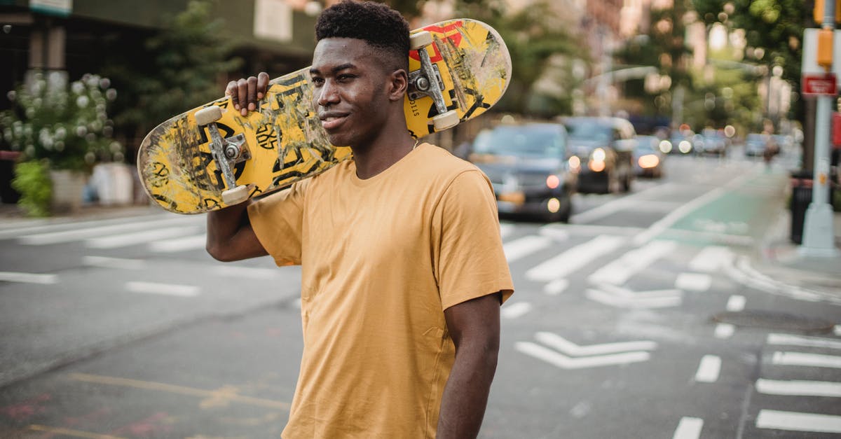 Does the current progress towards the next skill level carry over when training? - Smiling fit African American male skater in casual shirt standing with skateboard on shoulder on urban street and looking away contentedly