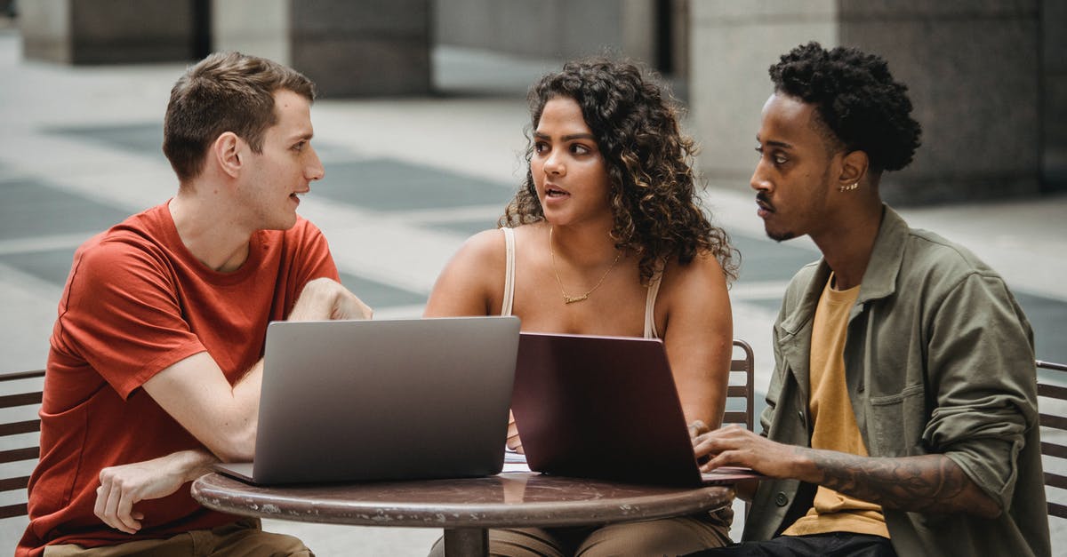 Does the Exp. Share also spread EVs to other members of the team? - Focused young multiethnic colleagues sitting at round table with laptops and discussing project details in city