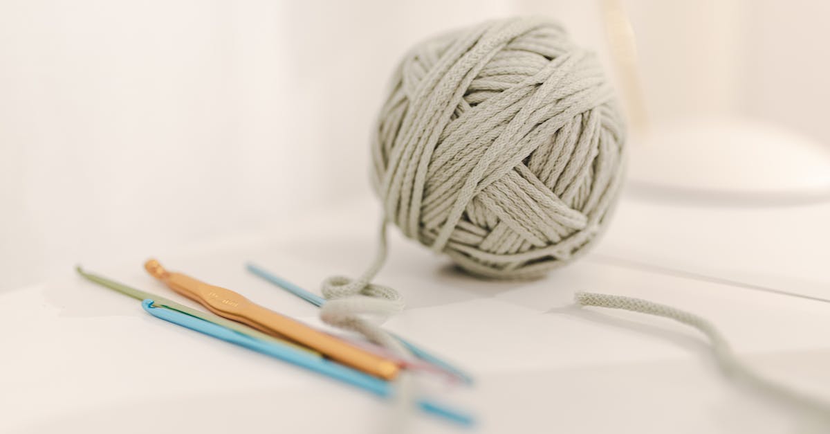 Does the quality of white items give different craft results? - Clew of gray knitting threads composed with different crochets on table on white background