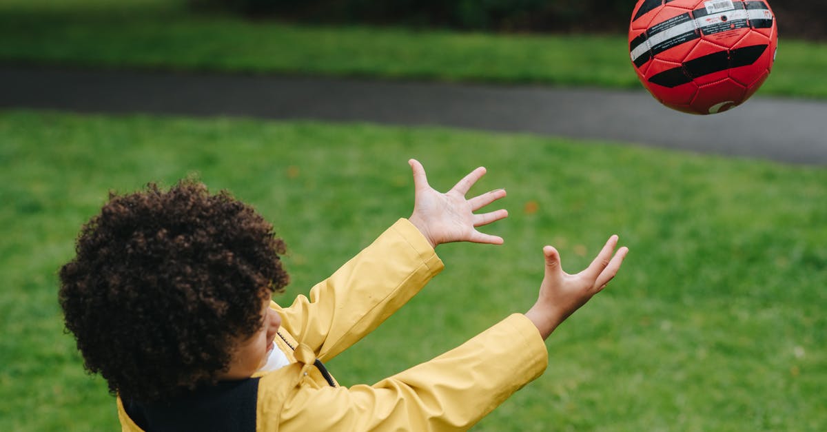 Does the throw bonus affect catch rate? - Side view of playful African American kid playing with red ball while standing on green lawn in park on blurred background