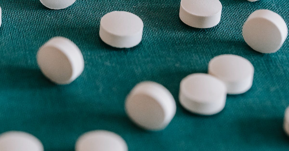 Does timely first aid speed up a wounded soldier's recovery? - Closeup of similar round white pills spilled on green tissue in random order