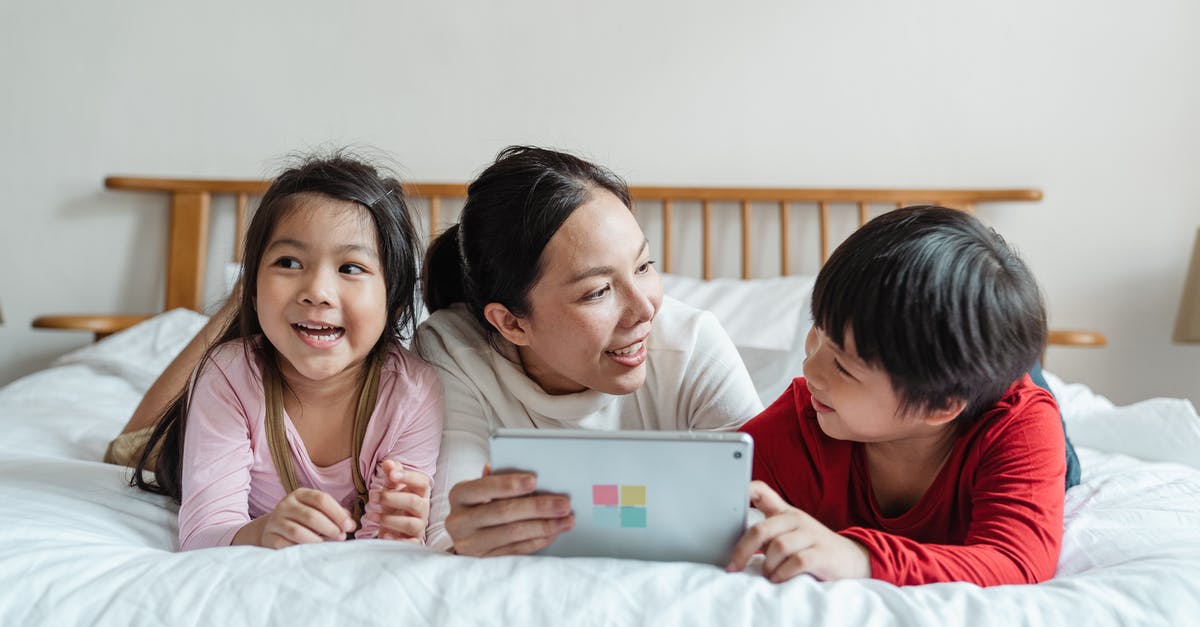 Does using Spark of light affect the story? - Full length smiling ethnic mother lying on stomach on comfortable bed with little daughter and son while using tablet in light room