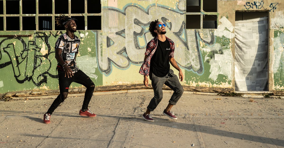 Don't have the needed software to perform this action? - Cheerful young ethnic men dancing on street near graffiti wall Don't have the needed software to perform this action? - Cheerful young ethnic men dancing on street near graffiti wall