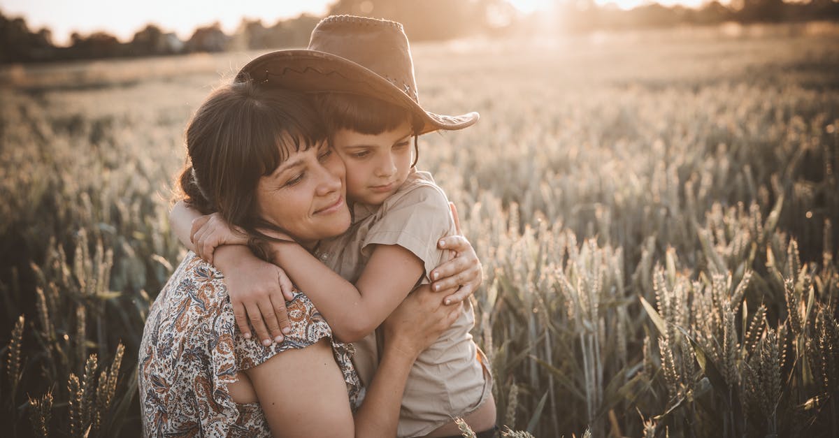 Doors affect villager mechanics in wheat farm? - Gentle mom with closed eyes hugging son wearing cowboy hat in rural wheat field at sunset
