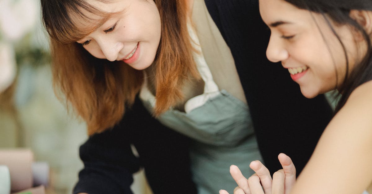 Dota 2 workshop content keeps downloading in the background [closed] - Side view of smiling Asian female in casual clothes and apron spending time with happy friend during workshop in daytime