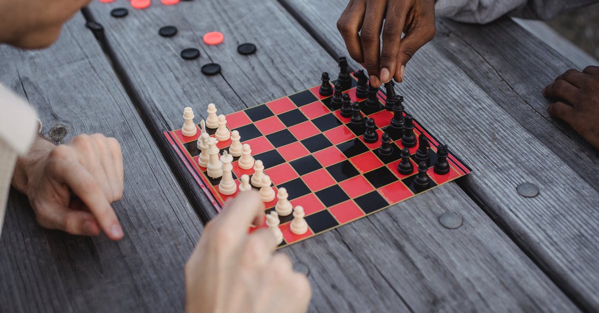 Double pay from game tournaments - Unrecognizable multiracial male millennials playing chess at wooden table Double pay from game tournaments - Unrecognizable multiracial male millennials playing chess at wooden table