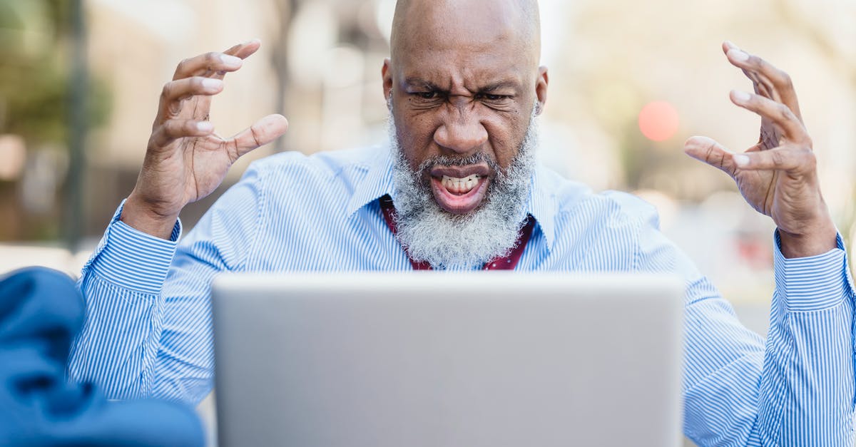 Dragon Boss strategy? - Wrathful focused bearded bald African American businessman in light blue shirt and tie watching laptop with raised hands while having video conversation Dragon Boss strategy? - Wrathful focused bearded bald African American businessman in light blue shirt and tie watching laptop with raised hands while having video conversation