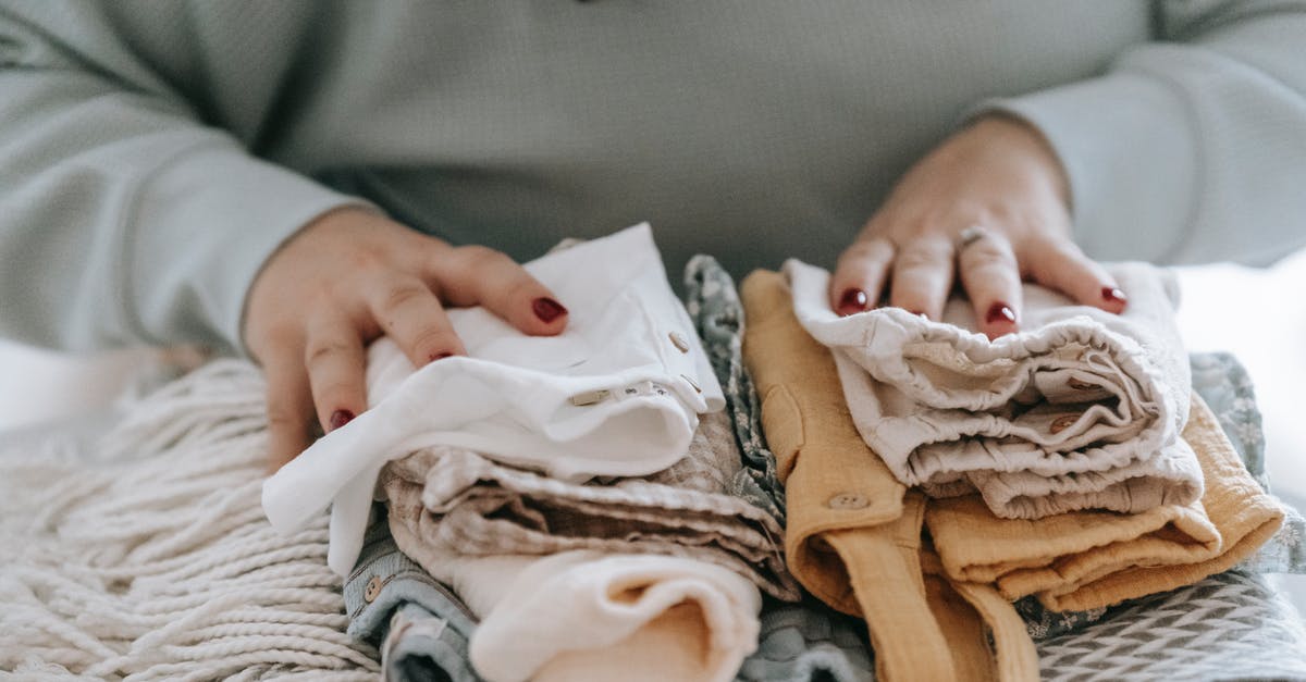 Dying Light the following: How to beat the Mother in final battle? - Crop faceless female with manicure arranging baby clothes on warm scarf while sitting at table in light room at home
