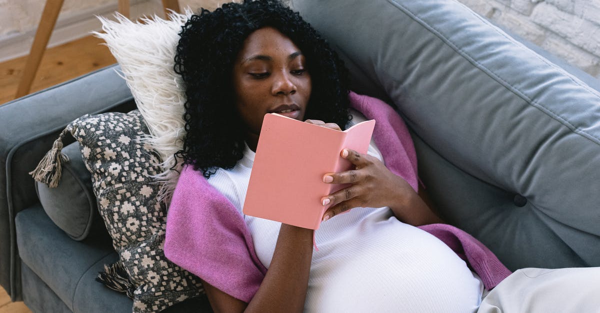 Dying Light the following: How to beat the Mother in final battle? - From above of focused pregnant African American female taking notes in notepad while resting on comfortable sofa in living room