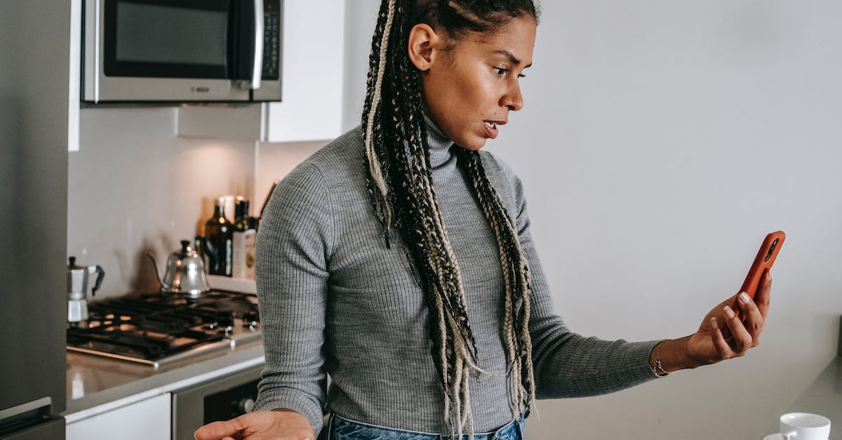 Early plot question - intro video and a battlefield - minor spoilers - Serious young black lady with Afro braids in casual clothes gesticulating while having unpleasant conversation via video chat on smartphone in modern kitchen