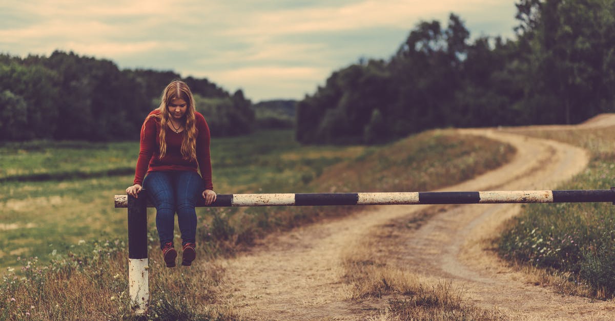 Effective Path Finding Mob Farm - Woman Sitting on Metal Gate Pass Beside Mud Road