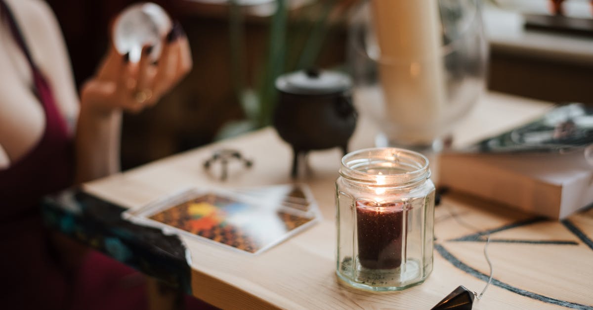 Enchanted Book separation - Crop anonymous female soothsayer with magic ball near shiny candle during divination process at home Enchanted Book separation - Crop anonymous female soothsayer with magic ball near shiny candle during divination process at home