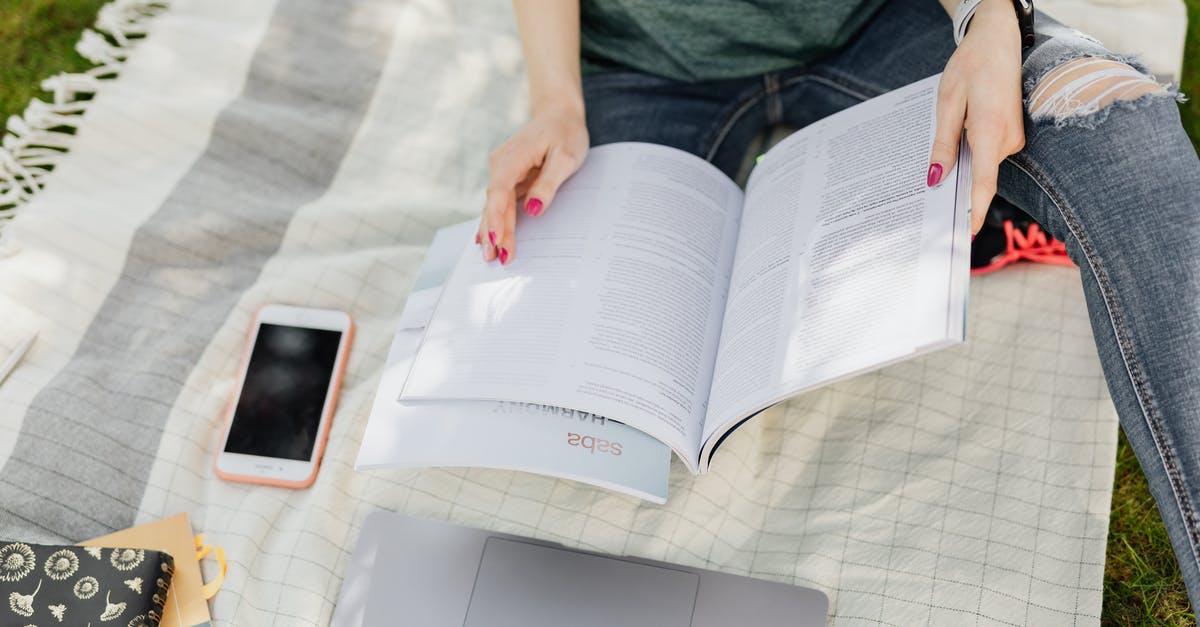 Enemies can't recover from my attacks - Crop university student reading textbooks on green campus lawn