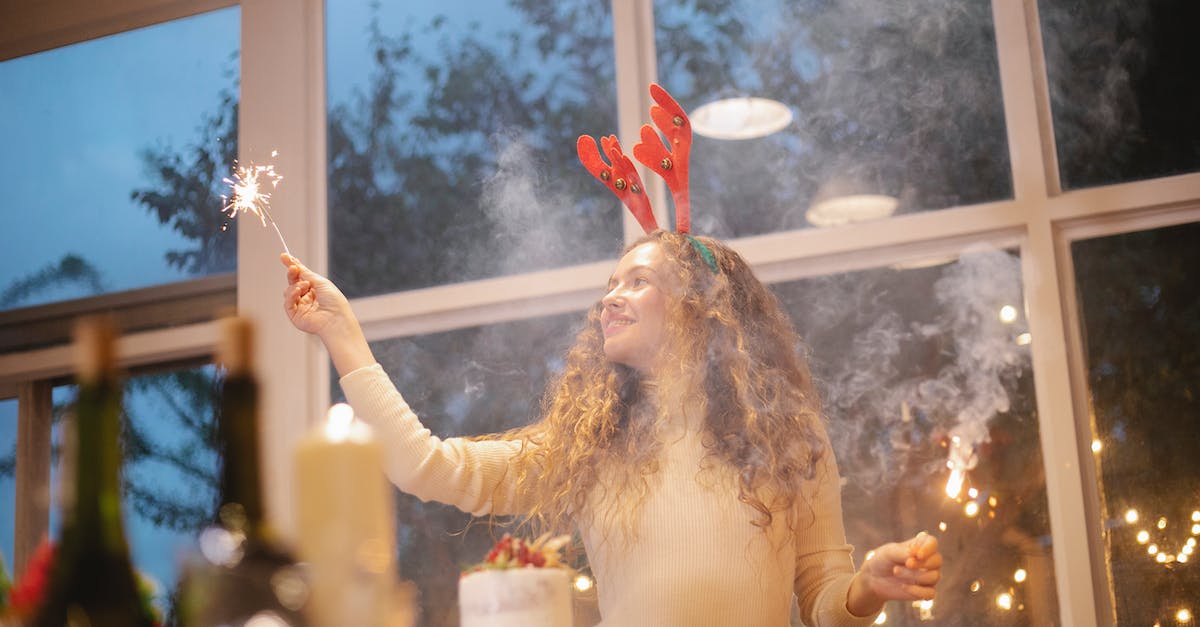 Europa Universalis Dutch Republic Event - Content female chef in decorative deer horns with shiny sparkler celebrating New Year holiday while looking away in house