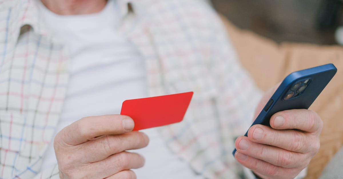 Everyone's attacking me and I'm unable to pay my bounty [duplicate] - A Person's Hands Holding a Card and a Cell Phone
