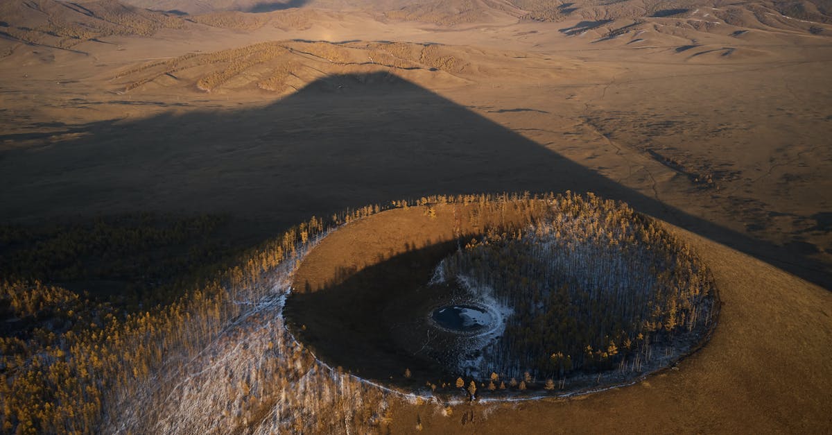 Extinction of the dwarves - Aerial view of Khorgo extinct volcano grown with forest and covered with snow casting huge dark shadow on valley in national park in Mongolia Extinction of the dwarves - Aerial view of Khorgo extinct volcano grown with forest and covered with snow casting huge dark shadow on valley in national park in Mongolia