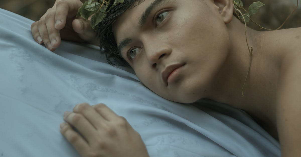 Fallout shelter: Where does the mystery man appear [duplicate] - Ethnic tanned male in green wreath lying on white sheet and looking away