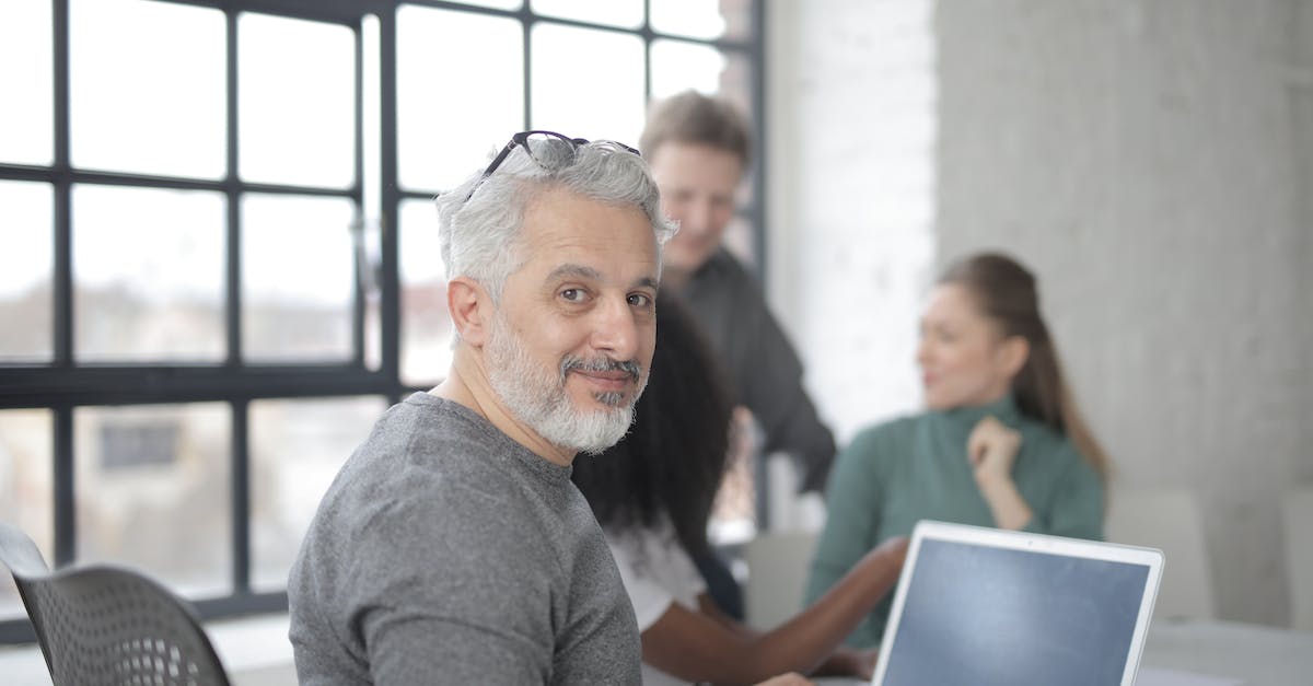 FIFA 15:UT Windows 10 black screen - Cheerful male worker sitting with laptop and multiethnic coworkers FIFA 15:UT Windows 10 black screen - Cheerful male worker sitting with laptop and multiethnic coworkers