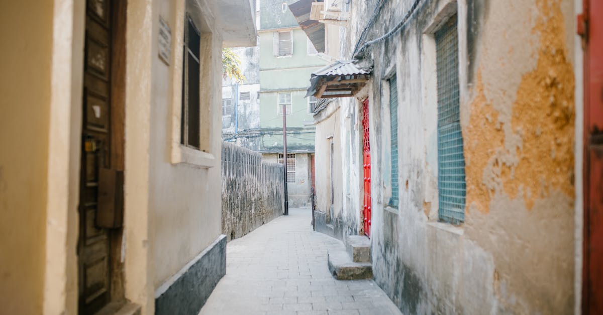 Finding way out of starting location? - Paved narrow street between aged stone residential houses with shabby facade in city