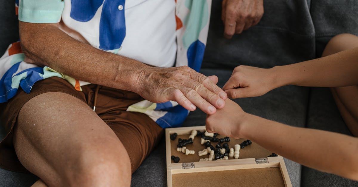 Finishing the game but not at 100% - Person in Blue Shirt and White Pants Holding Black and White Chess Piece