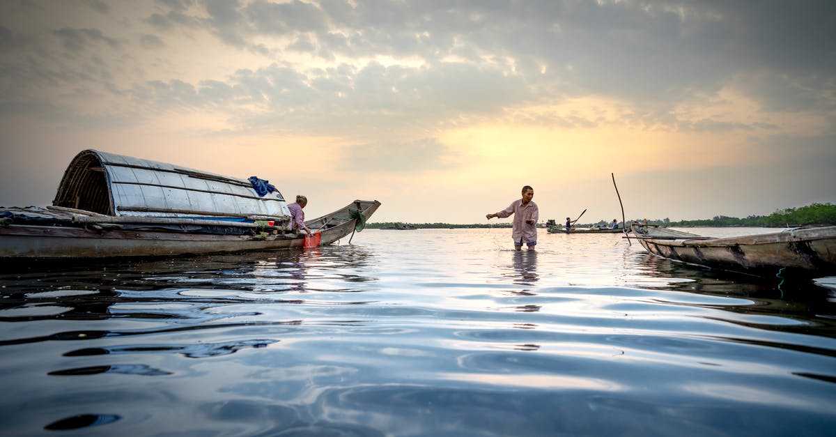 Fishing schools in shallow water - People of local village with fishing equipment on boat in shallow water under cloudy sky Fishing schools in shallow water - People of local village with fishing equipment on boat in shallow water under cloudy sky