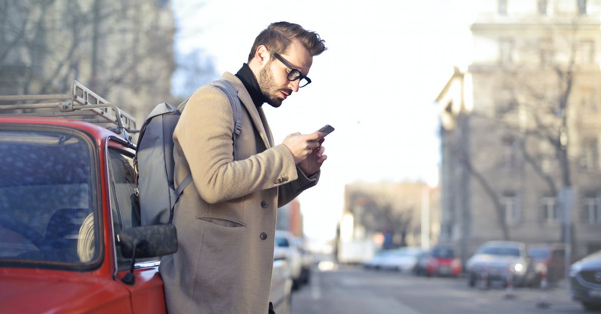 FOB holding too much resource materials and vehicles - Man in Beige Coat Holding Phone Leaning on Red Vehicle