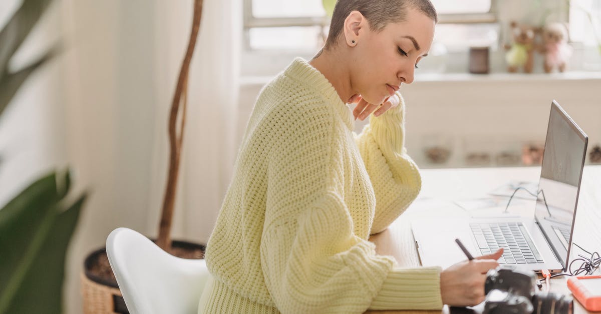 For PC gaming on external storage, should I use Flash or HDD (hard disk drive)? - Side view of serious female with short hair drawing with stylus while editing photos at table with photo camera during work in room with green plant