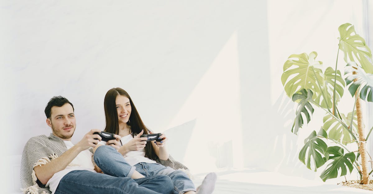 Free games on PlayStation Network and PlayStation Plus - Content man in jeans with game pad lying near positive girlfriend on bed near potted plant on sunny day while entertaining together