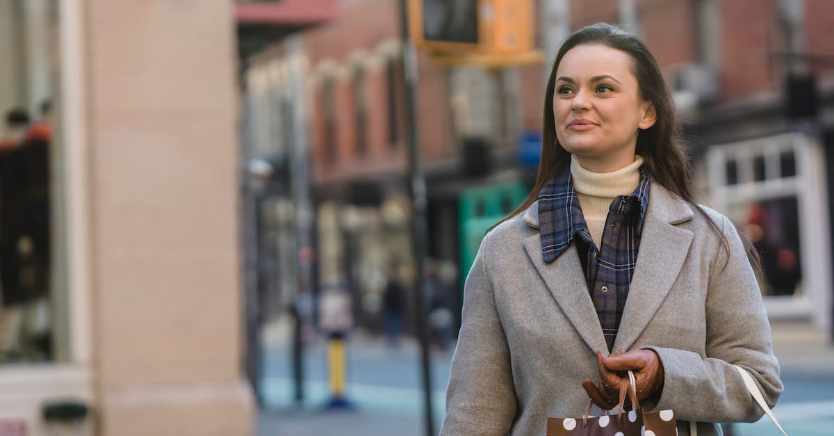 Free gift timer in crossy road - Dreamy young woman in warm coat and gloves with gift packages and purse strolling in street near buildings and road while looking away in town in daylight Free gift timer in crossy road - Dreamy young woman in warm coat and gloves with gift packages and purse strolling in street near buildings and road while looking away in town in daylight
