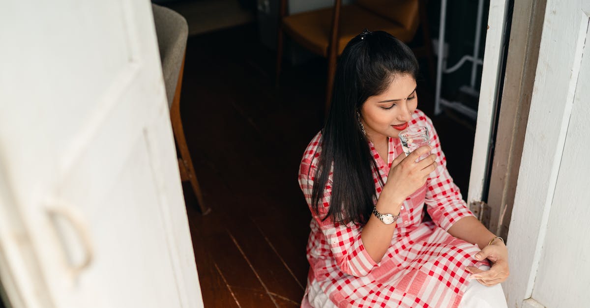 From the water to the door - Young brunette drinking water while sitting in doorway From the water to the door - Young brunette drinking water while sitting in doorway