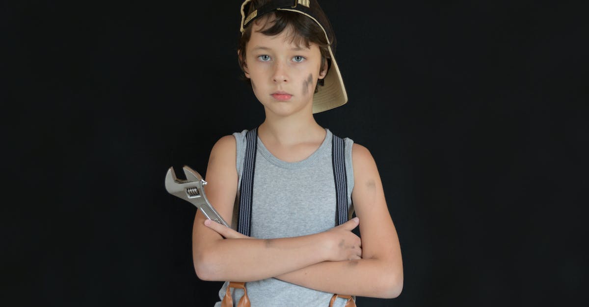 Game corrupted; how can I fix it? - Serious preteen boy with dirty face wearing vehicle technician outfit standing with arms folded and wrench against black background while looking at camera