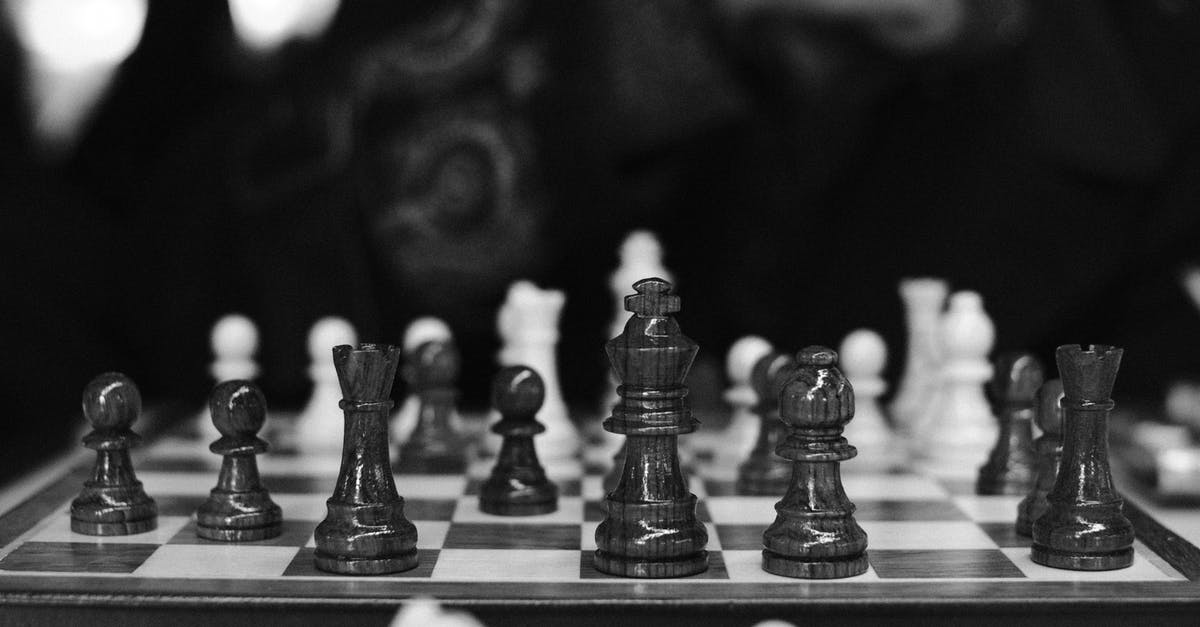 Game minimizing during play - Black and white of wooden chess pieces placed on chessboard placed in dark room against blurred background