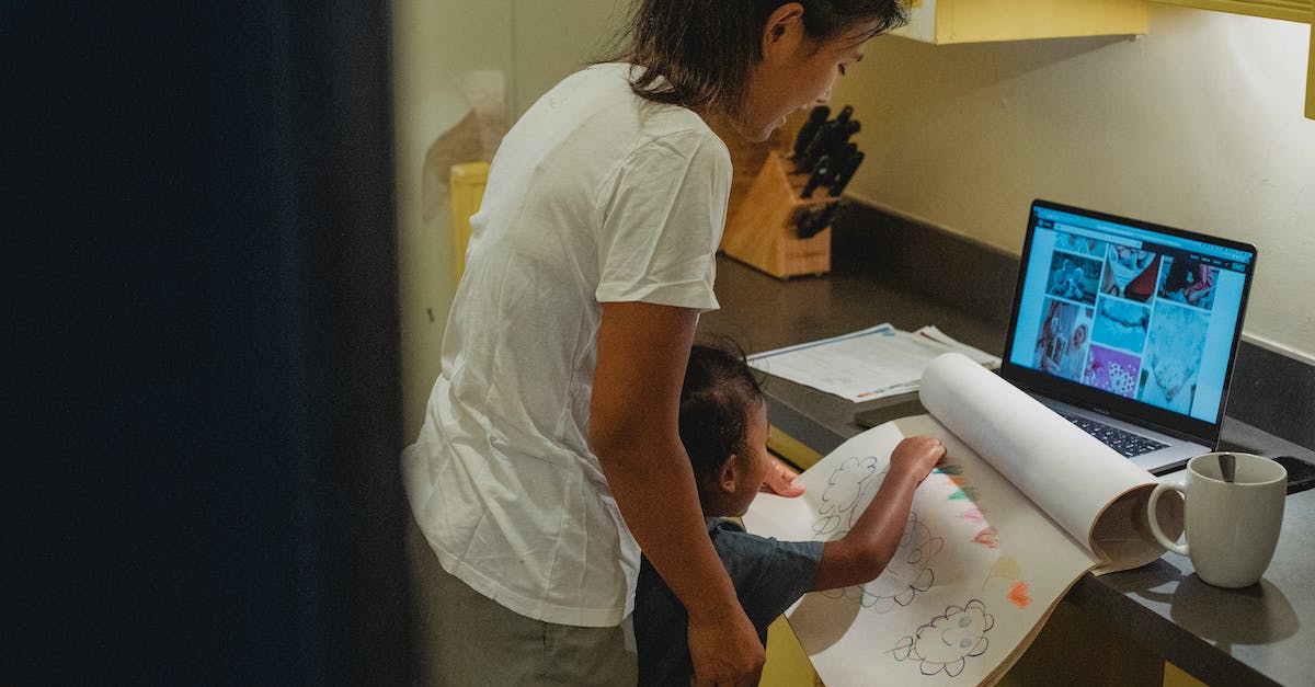 Getting Error When trying to play Counter strike 1.6 - Side view positive ethnic child painting on paper while standing near mother and counter with laptop at home