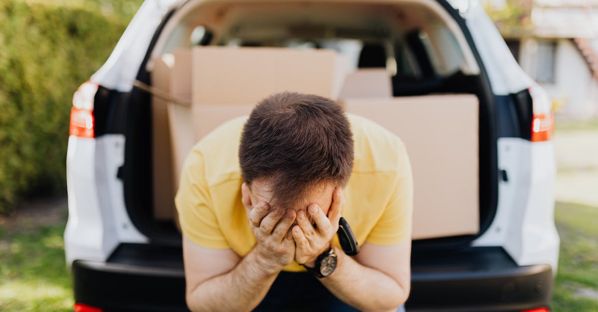 Getting real tired of the other players being cheeky - Faceless frustrated tired male wearing casual outfit sitting on car luggage boot and covering face with hands during relocation on sunny summer day Getting real tired of the other players being cheeky - Faceless frustrated tired male wearing casual outfit sitting on car luggage boot and covering face with hands during relocation on sunny summer day