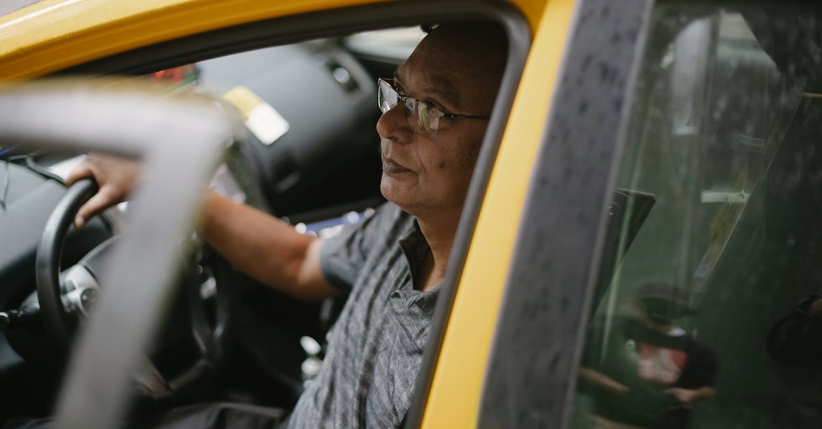 Getting the most experience out of a taxi - Middle aged driver at steering wheel of yellow automobile