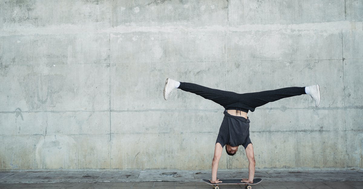 Ghoul acquiring abilities - Anonymous guy in activewear doing handstand on skateboard while riding alone near concrete wall and pavement Ghoul acquiring abilities - Anonymous guy in activewear doing handstand on skateboard while riding alone near concrete wall and pavement