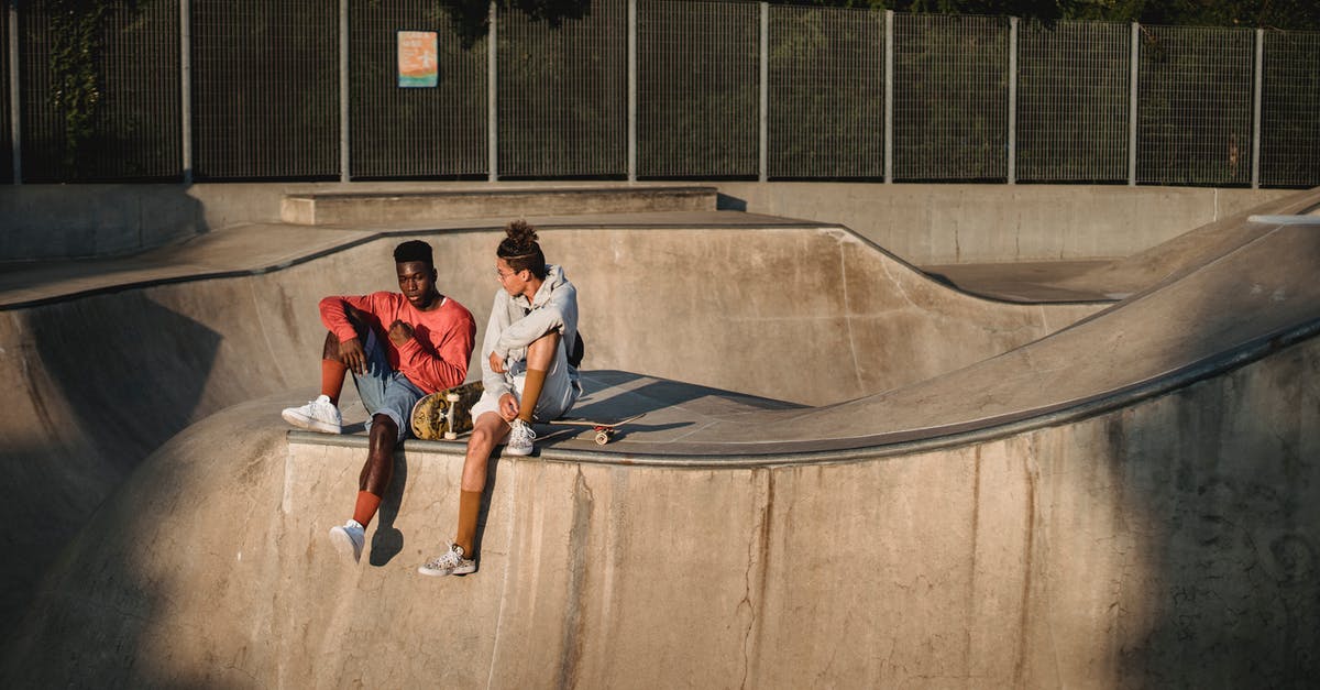 Ghoul acquiring abilities - Young diverse male friends spending free time together while sitting with skateboards on ramp in skate park on summer sunny day Ghoul acquiring abilities - Young diverse male friends spending free time together while sitting with skateboards on ramp in skate park on summer sunny day