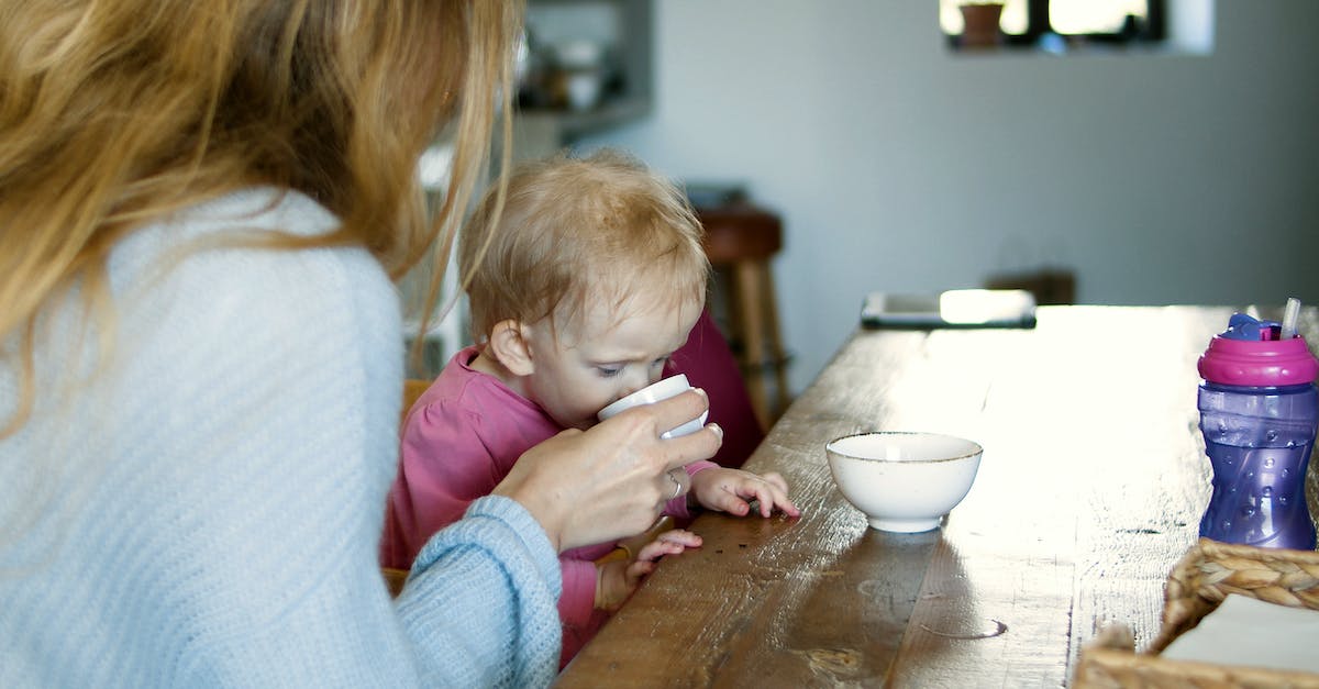 Give Baby Items - Mother Giving Drink to a Baby in Pink Long Sleeve Shirt Give Baby Items - Mother Giving Drink to a Baby in Pink Long Sleeve Shirt