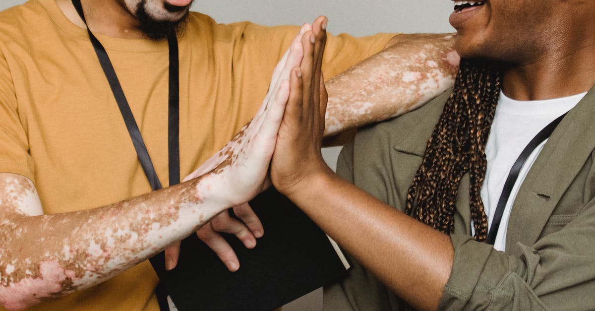 Good strategies for dealing with Lil' Hunter? - Crop smiling African American male with vitiligo skin giving high five to colleague in studio