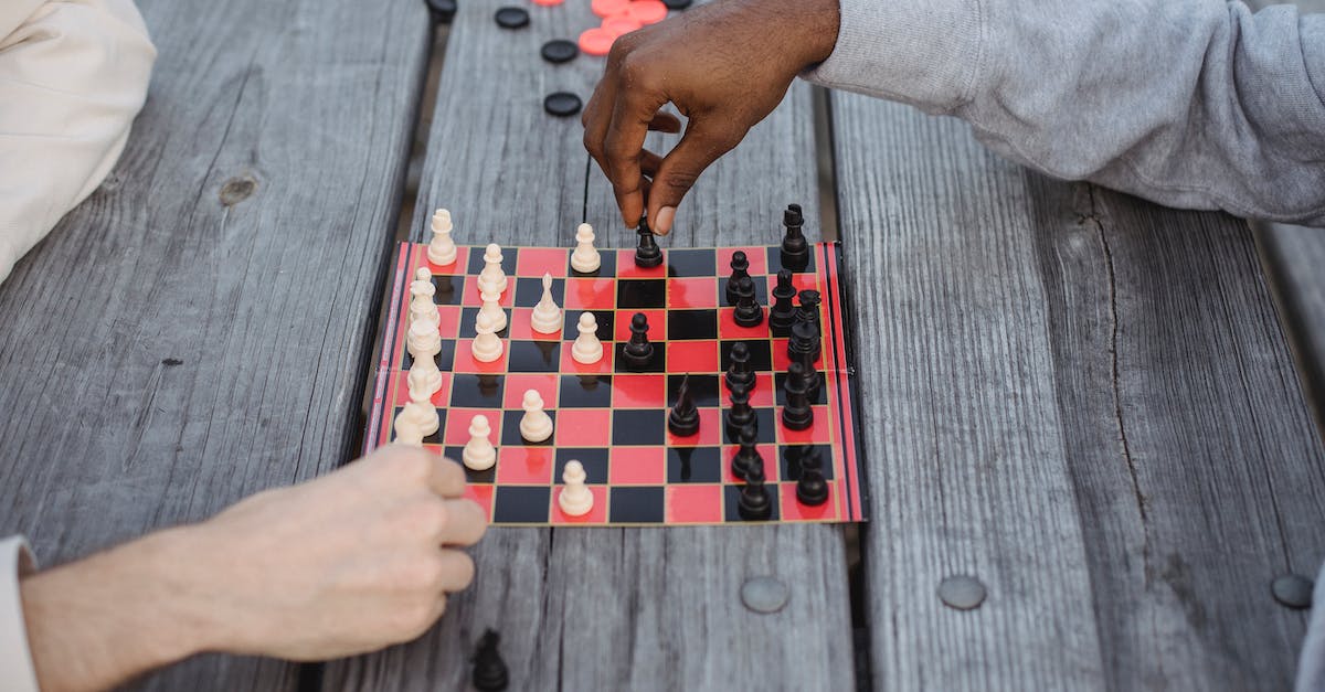 Google Play Games: accessing player profiles from a web browser - From above of crop anonymous multiethnic friends playing chess sitting at wooden table